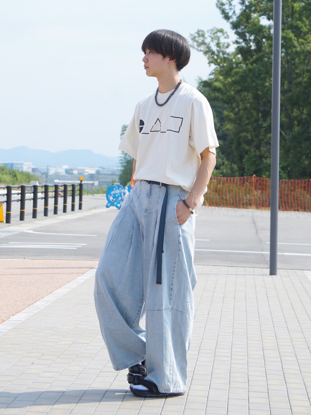 ベージュ系のTシャツ/カットソー、ブルー系のデニムパンツ、ホワイト系のサンダルを着用したメンズの夏コーディネートの2枚目の写真