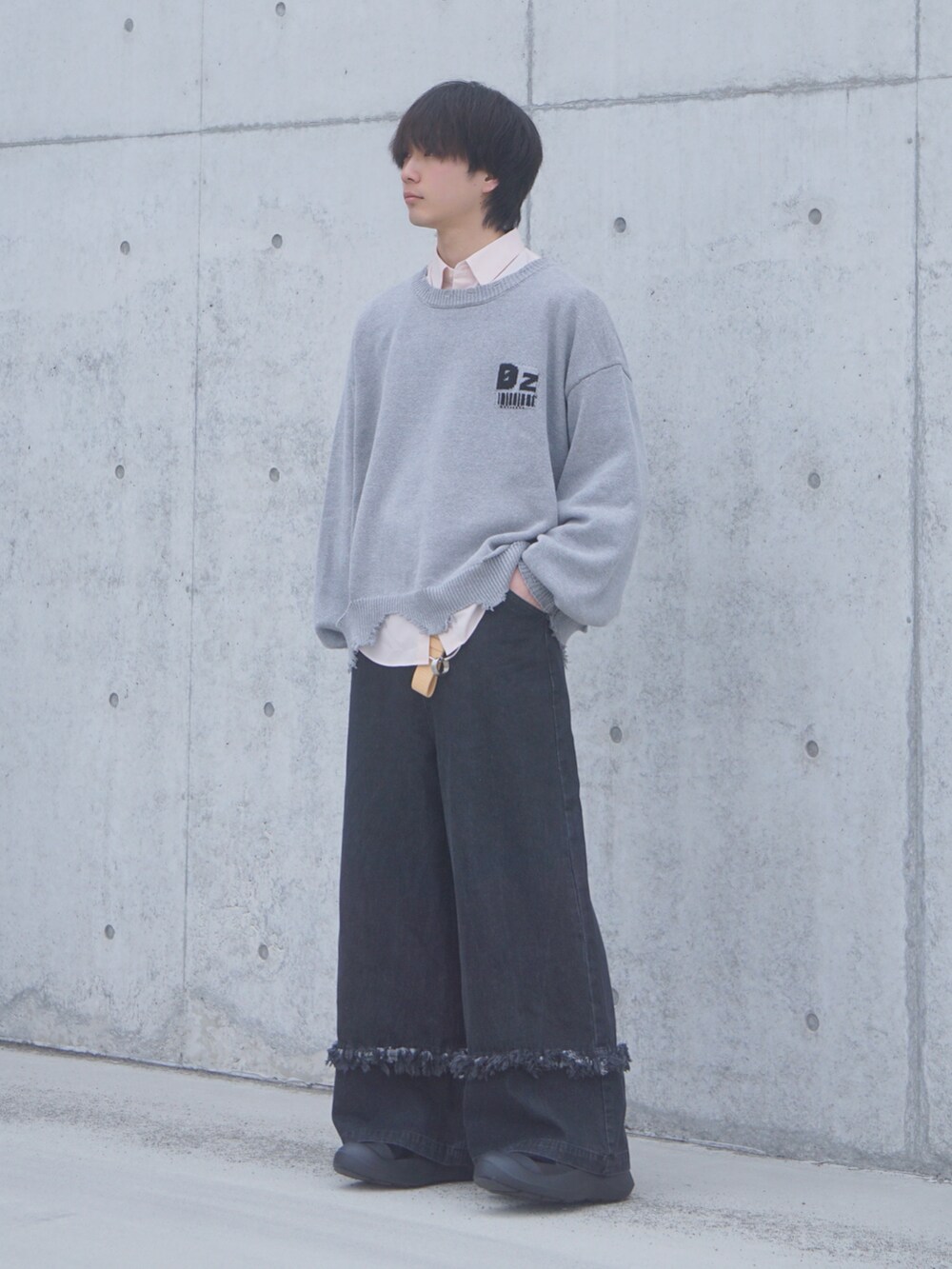 グレー系のニット/セーター、ブラック系のデニムパンツ、ブラック系のスニーカーを着用したメンズの春コーディネートの2枚目の写真
