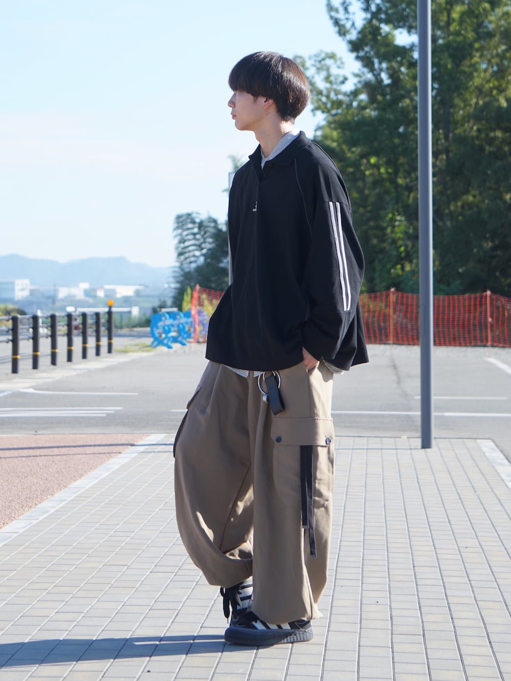 ブラック系のポロシャツ、ホワイト系のシャツ/ブラウス、ベージュ系のカーゴパンツを着用したメンズの秋コーディネートの2枚目の写真