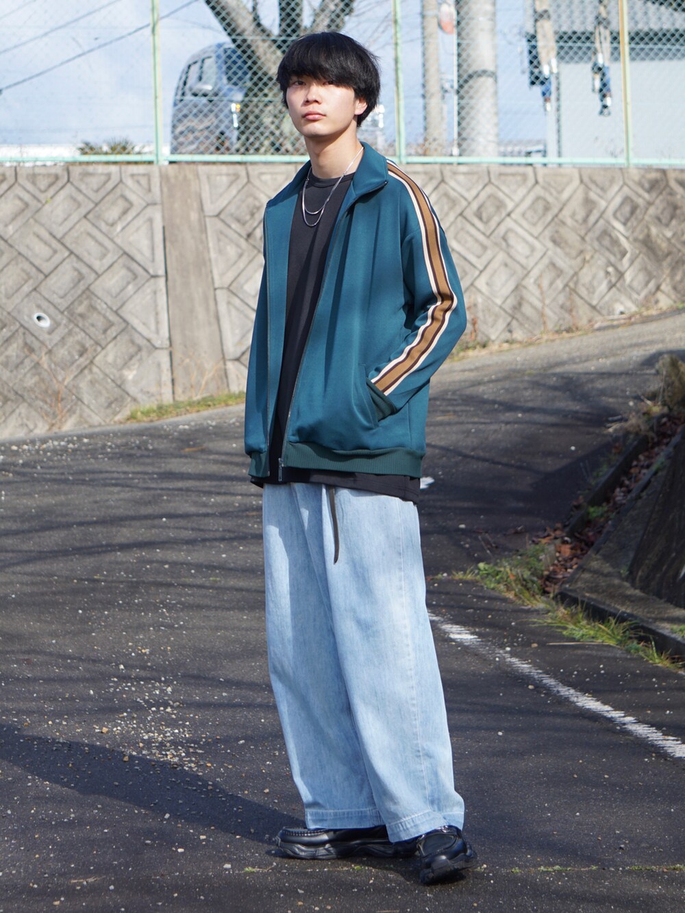 グリーン系のブルゾン、ブラック系のTシャツ/カットソー、ブルー系のデニムパンツを着用したメンズの冬コーディネートの2枚目の写真