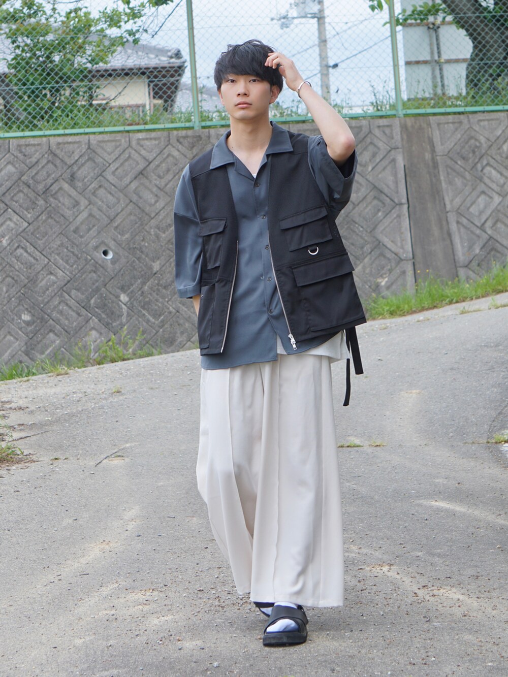 ベージュ系のスラックス、ブラック系のベスト、グレー系のシャツ/ブラウスを着用したメンズの春コーディネートの2枚目の写真