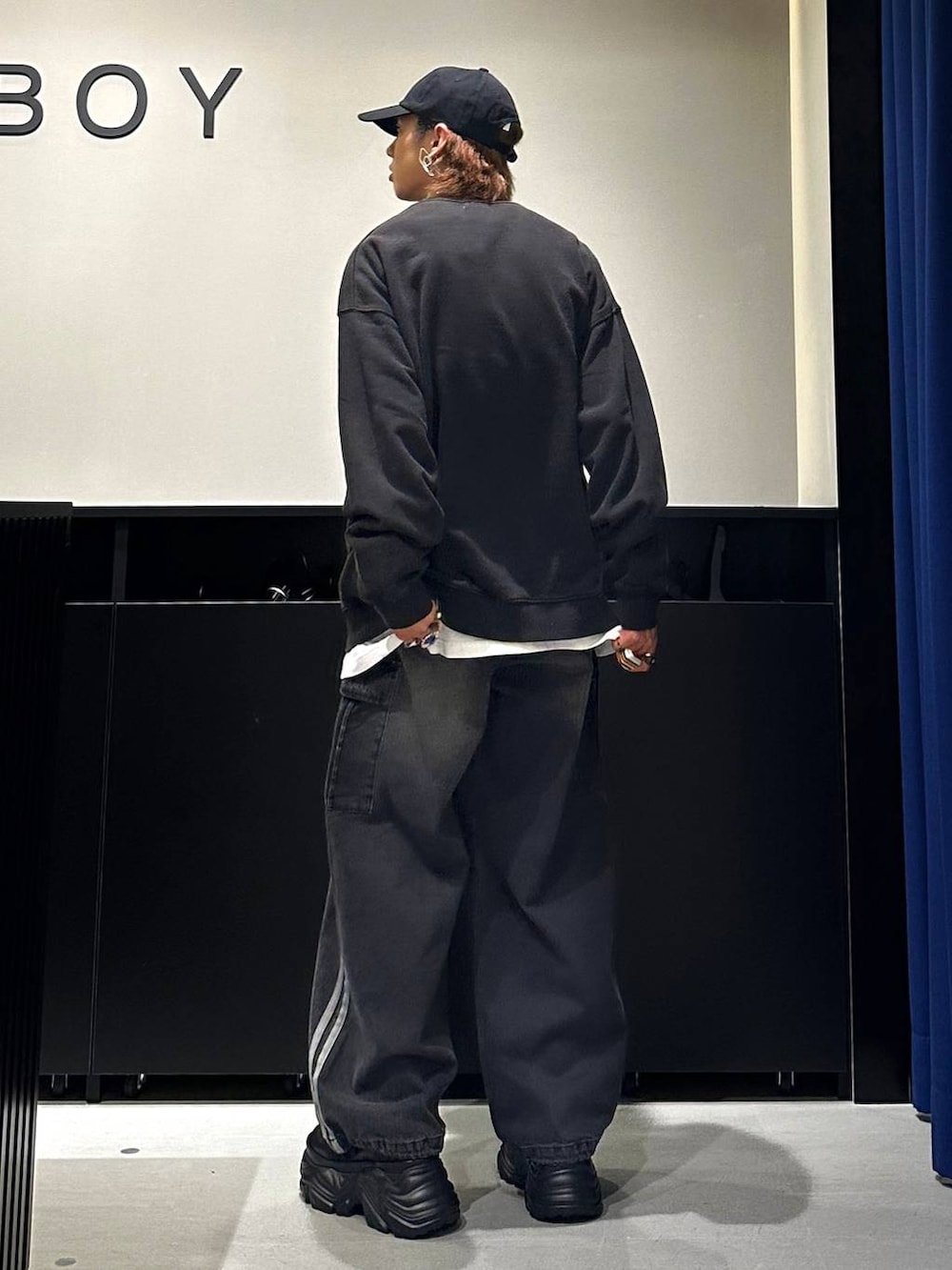 ブラック系のデニムパンツ、ブラック系のスウェット、シルバー系のネックレスを着用したメンズの秋コーディネートの3枚目の写真