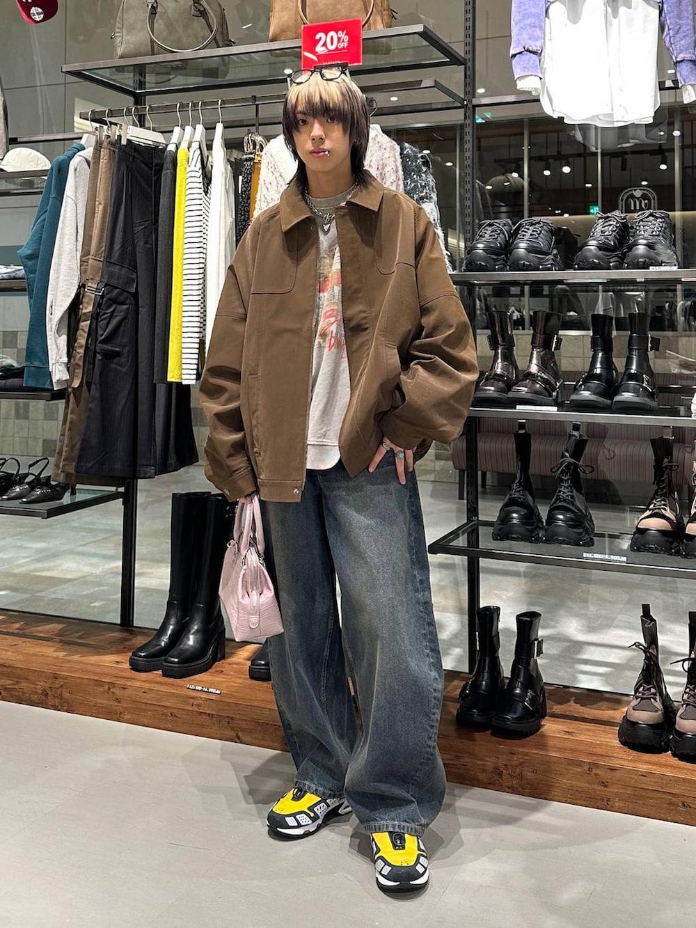 ブルー系のデニムパンツ、ピンク系のハンドバッグ、ベージュ系のスウェットを着用したメンズの冬コーディネートの2枚目の写真