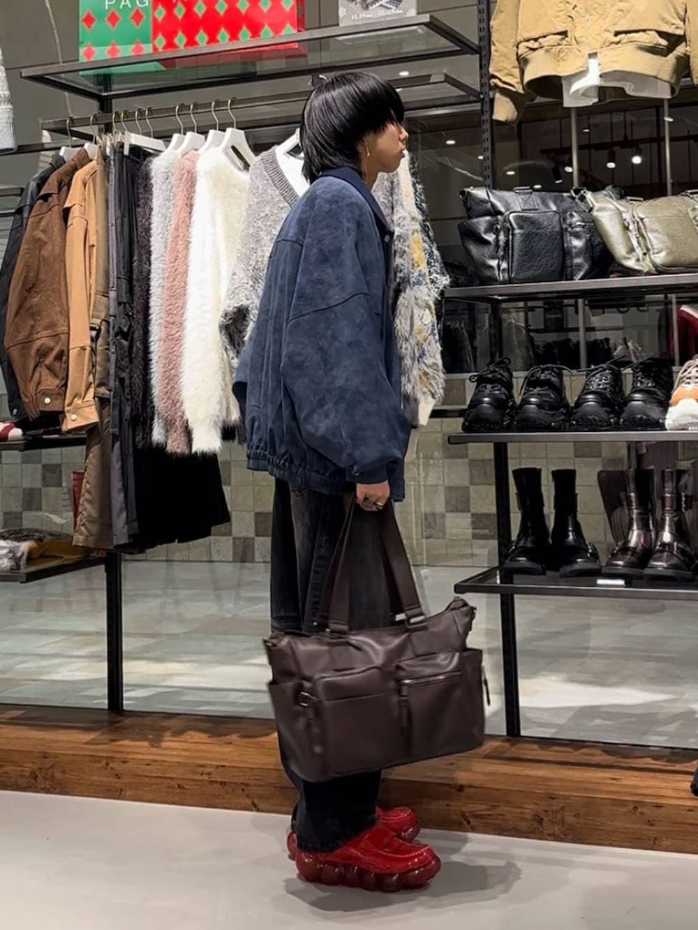 ブラウン系のボストンバッグ、ブルー系のブルゾン、ブラック系のデニムパンツを着用したメンズの秋コーディネートの3枚目の写真