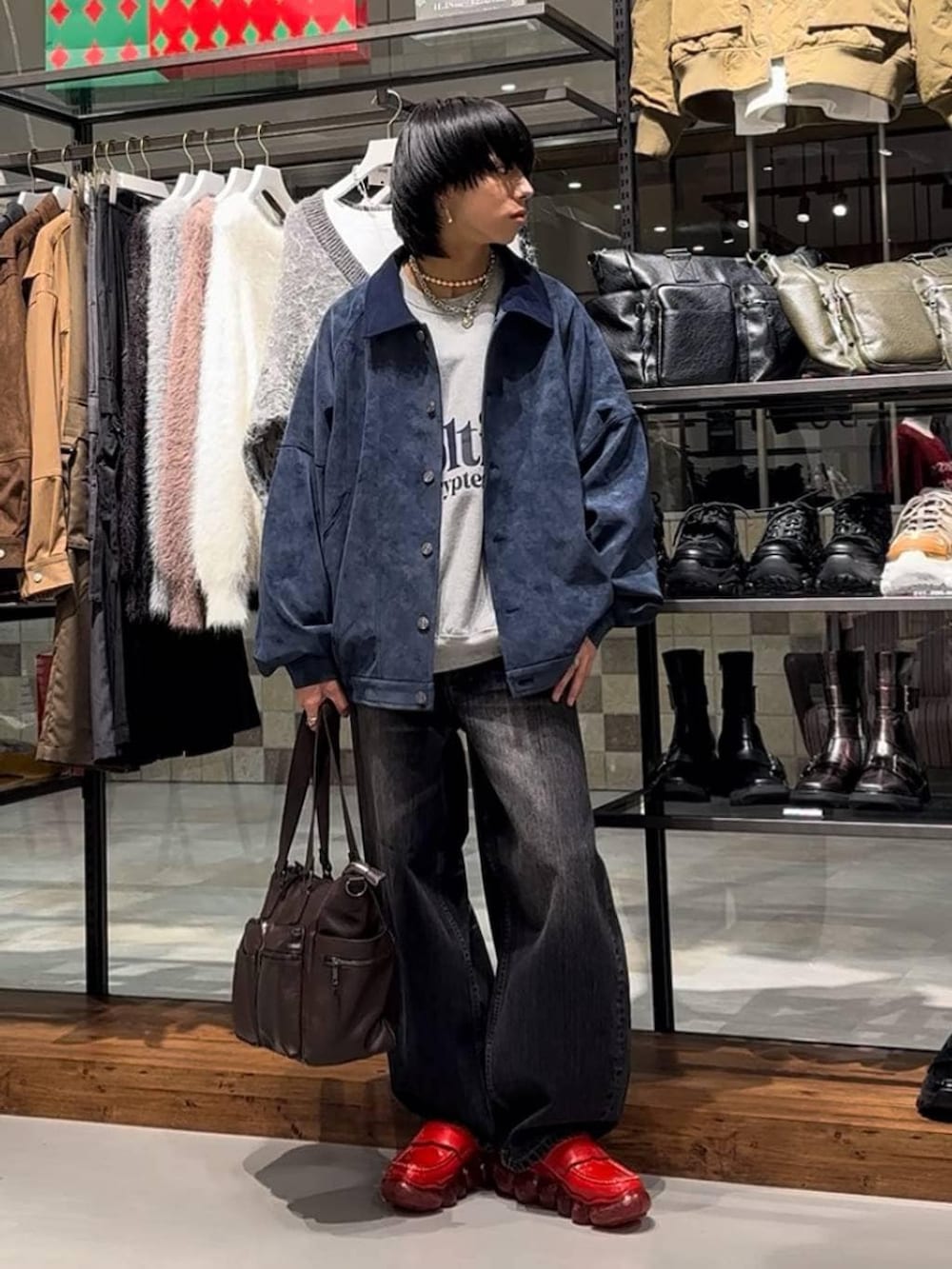 ブラウン系のボストンバッグ、ブルー系のブルゾン、ブラック系のデニムパンツを着用したメンズの秋コーディネートの2枚目の写真