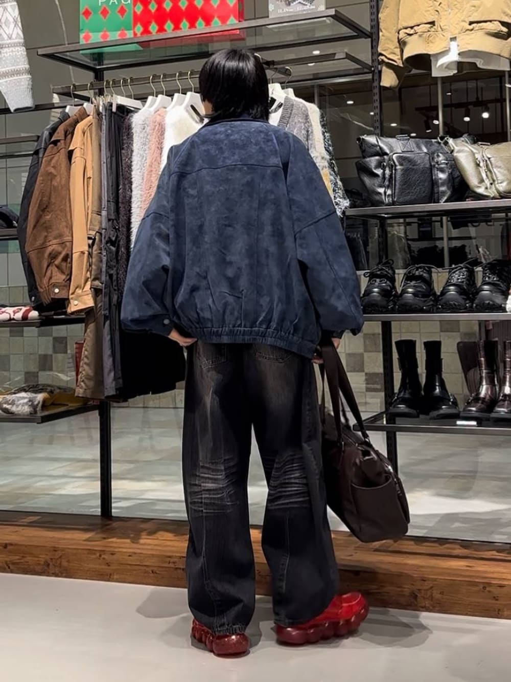 ブラウン系のボストンバッグ、ブルー系のブルゾン、ブラック系のデニムパンツを着用したメンズの秋コーディネートの5枚目の写真