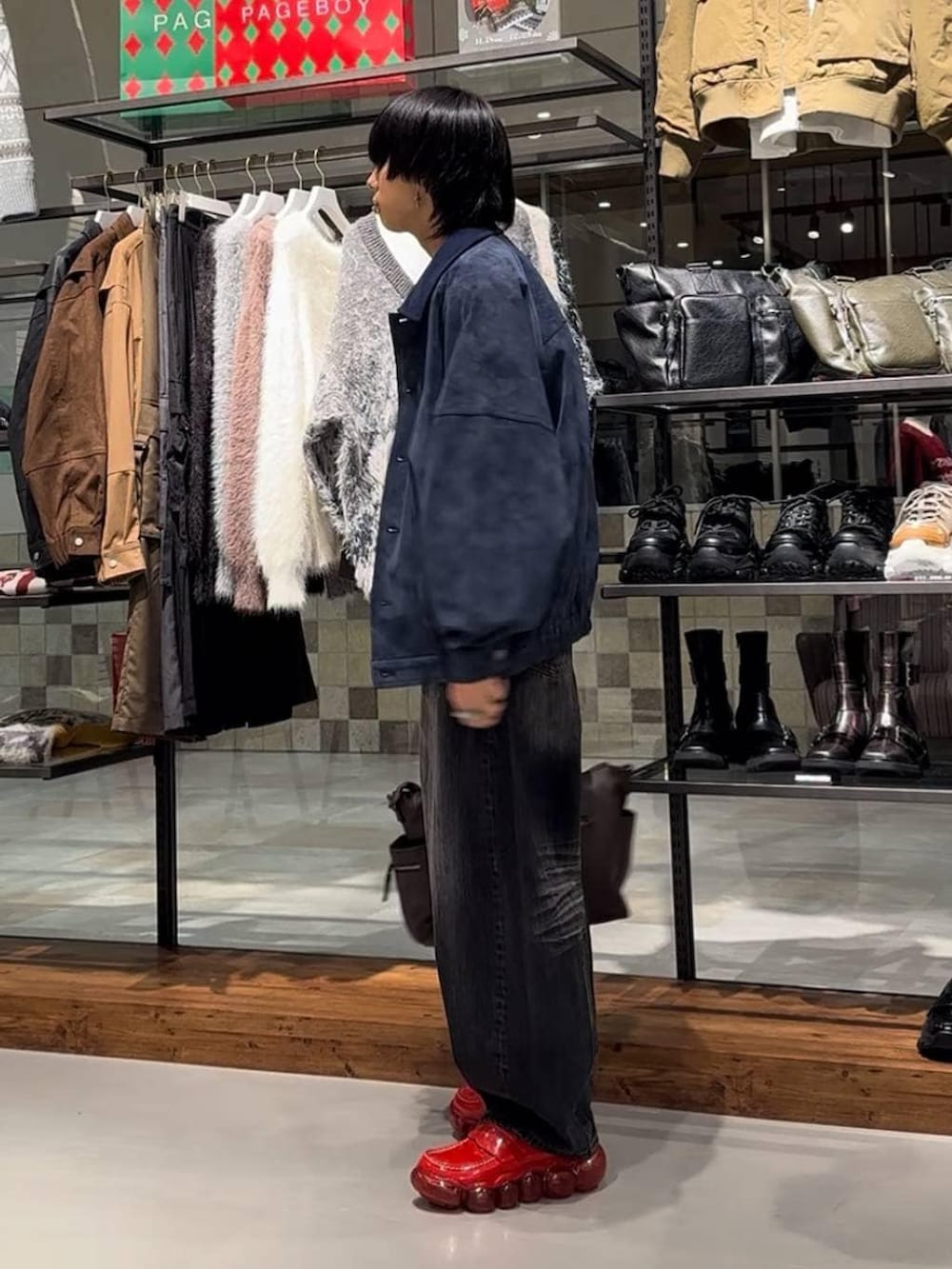 ブラウン系のボストンバッグ、ブルー系のブルゾン、ブラック系のデニムパンツを着用したメンズの秋コーディネートの4枚目の写真