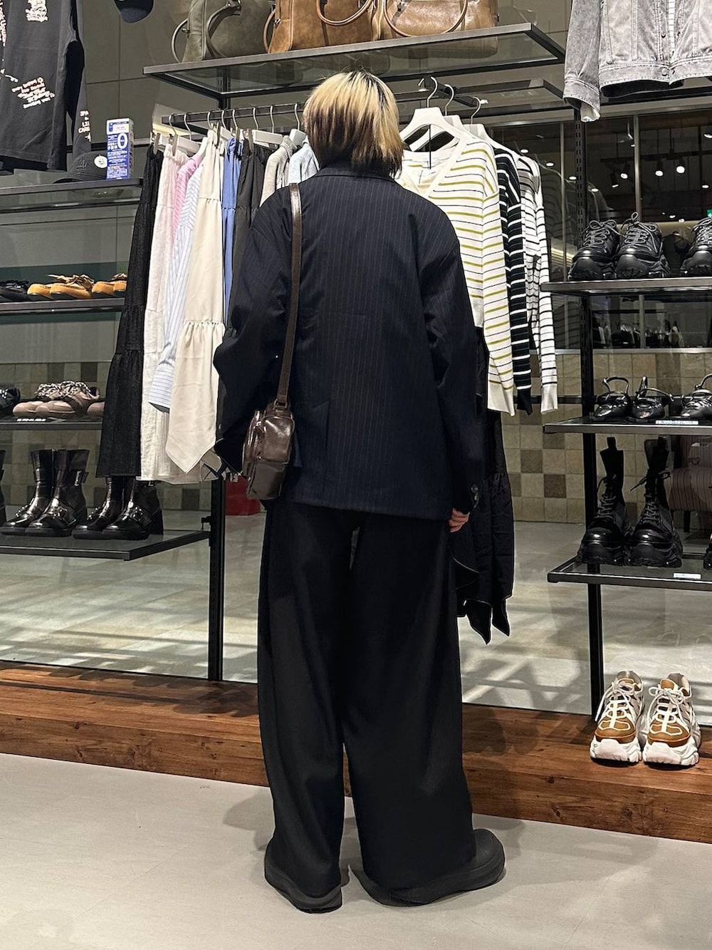 ブラック系のスラックス、ブラウン系のショルダーバッグ、ピンク系のTシャツ/カットソーを着用したメンズの春コーディネートの5枚目の写真