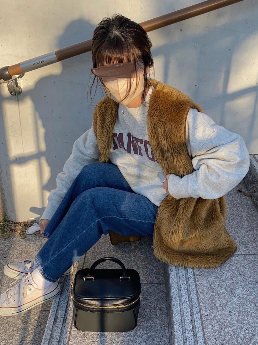 ブラウン系のベスト、グレー系のスウェット、ホワイト系のスニーカーを着用したレディースの春コーディネートの2枚目の写真