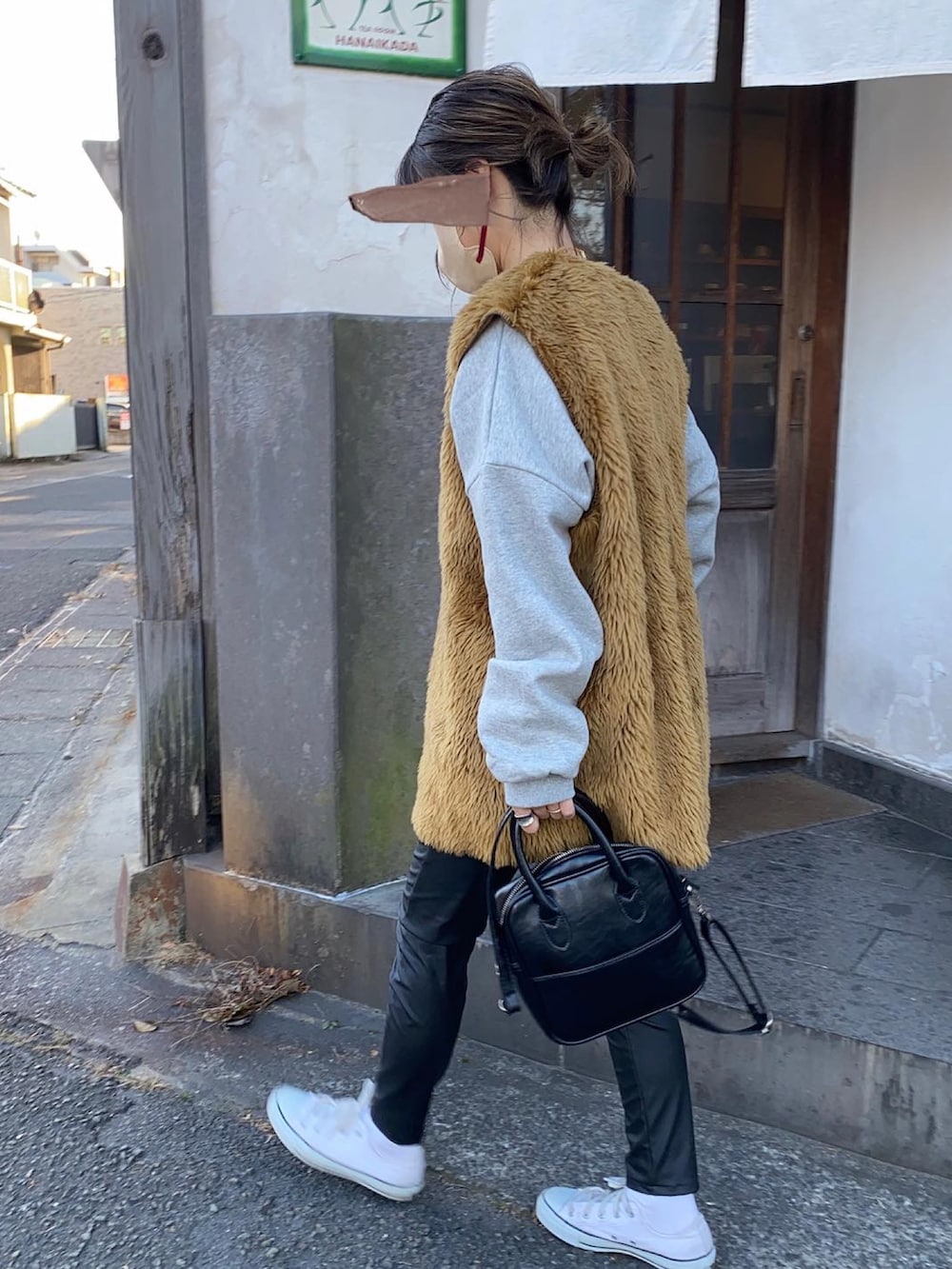 ブラウン系のベスト、ブラック系のその他パンツ、ホワイト系のスニーカーを着用したレディースの冬コーディネートの2枚目の写真