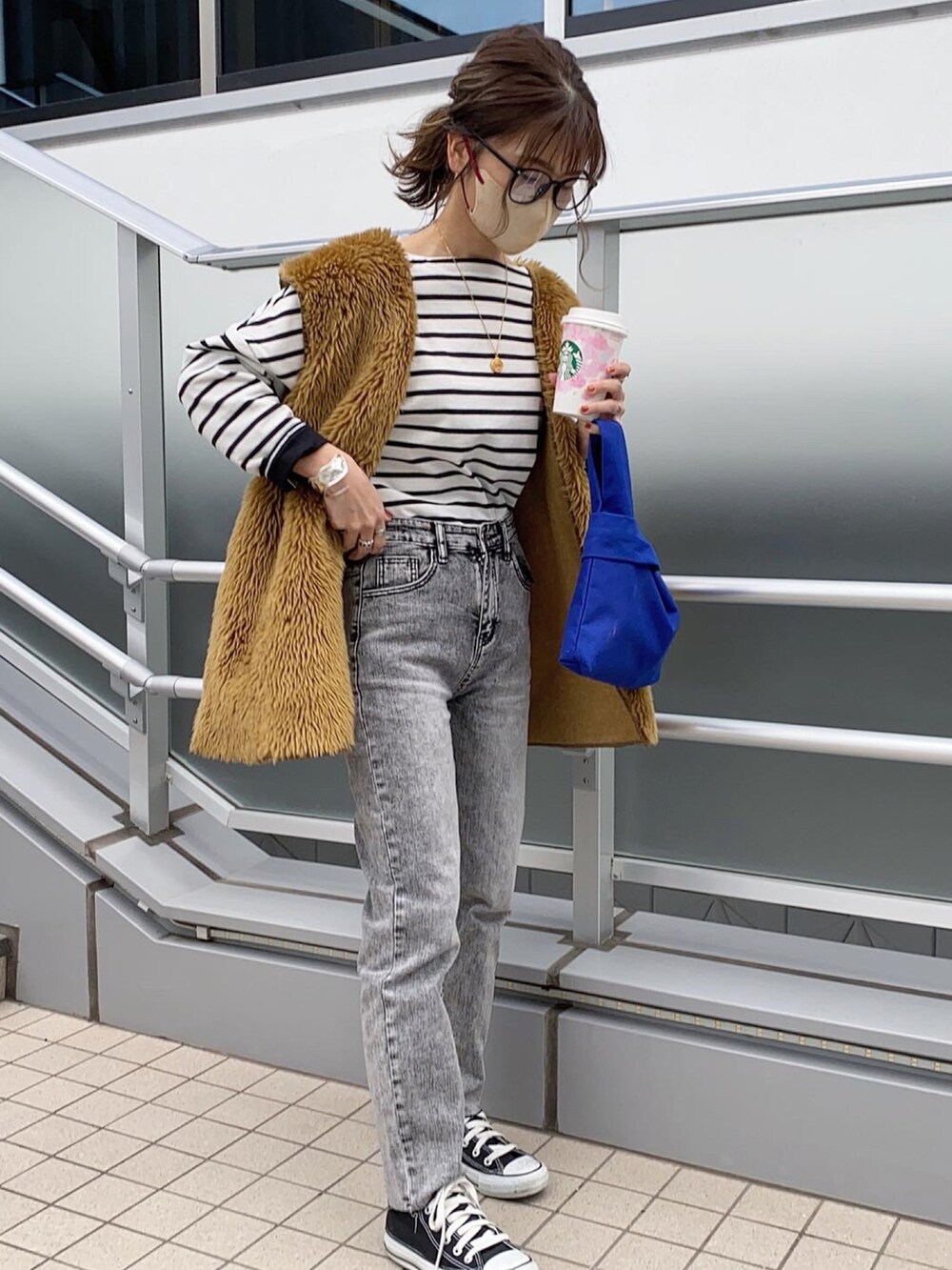 ブラック系のスニーカー、ホワイト系のTシャツ/カットソー、ブラウン系のベストを着用したレディースの春コーディネートの2枚目の写真