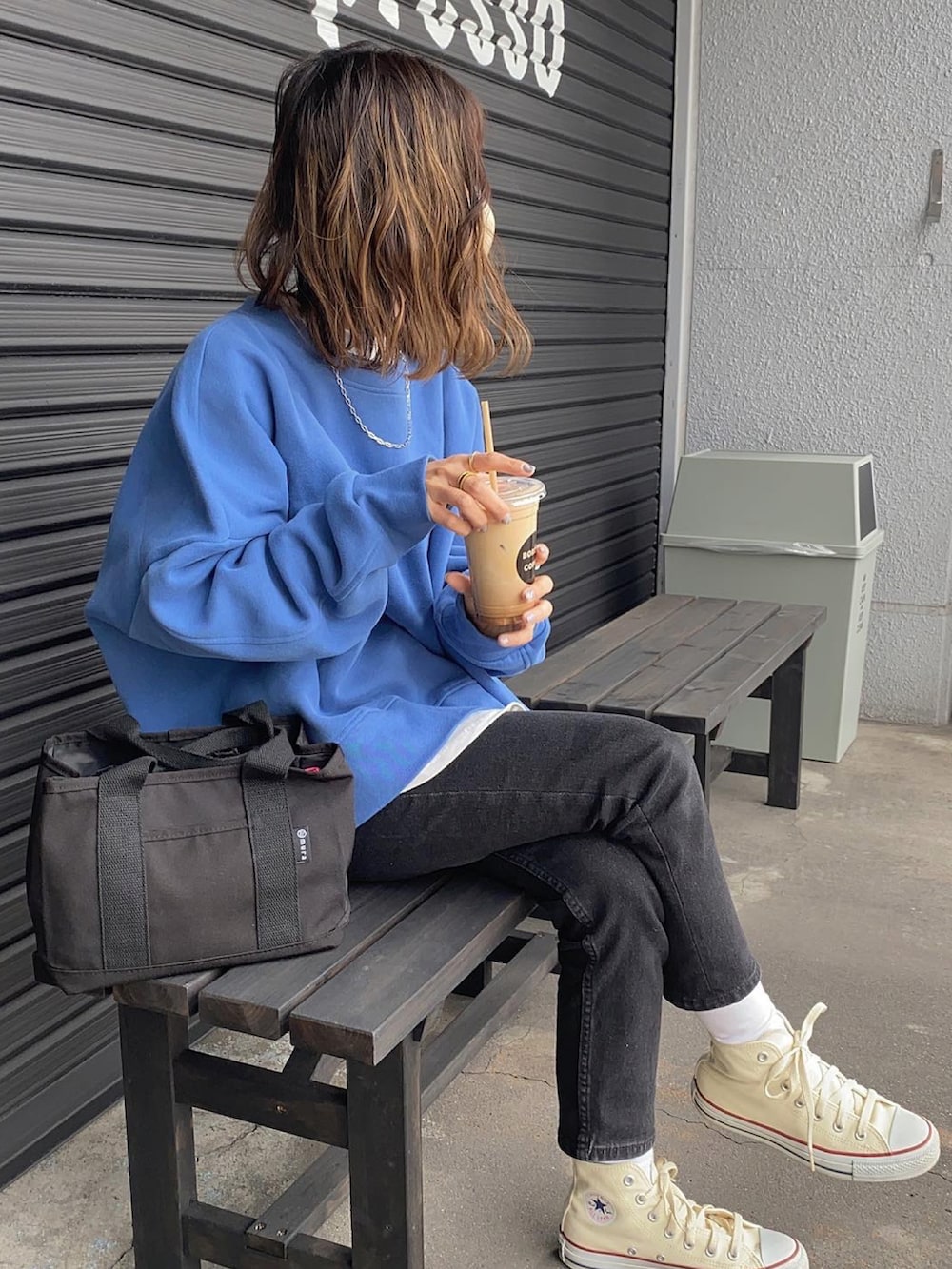 ブルー系のスウェット、ホワイト系のスニーカー、ブラック系のデニムパンツを着用したレディースの春コーディネートの2枚目の写真