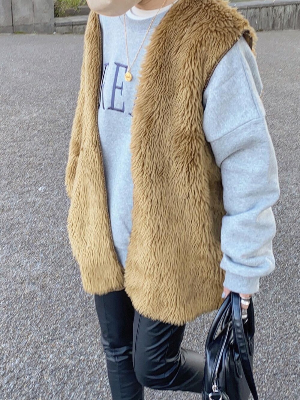 ブラウン系のベスト、ブラック系のその他パンツ、ホワイト系のスニーカーを着用したレディースの冬コーディネートの4枚目の写真