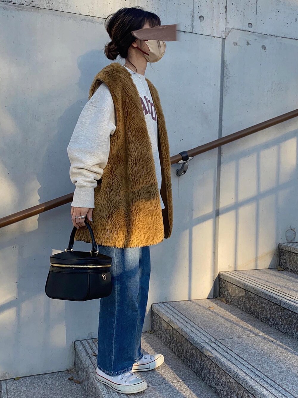 ブラウン系のベスト、グレー系のスウェット、ホワイト系のスニーカーを着用したレディースの春コーディネートの3枚目の写真