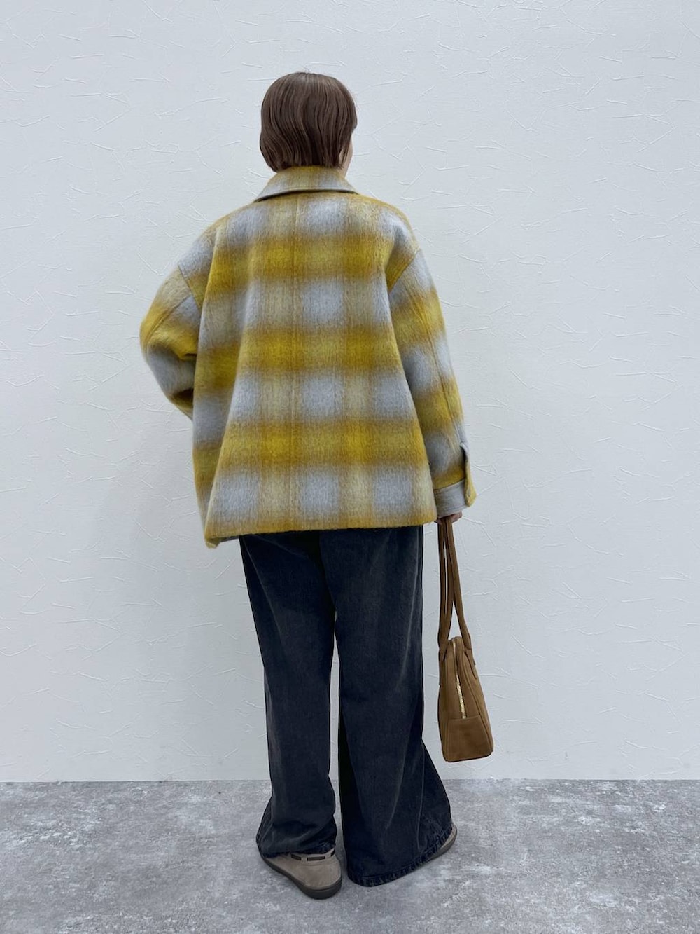 ブラック系のデニムパンツ、イエロー系のその他アウター、グレー系のモカシン/デッキシューズを着用したレディースの秋コーディネートの3枚目の写真