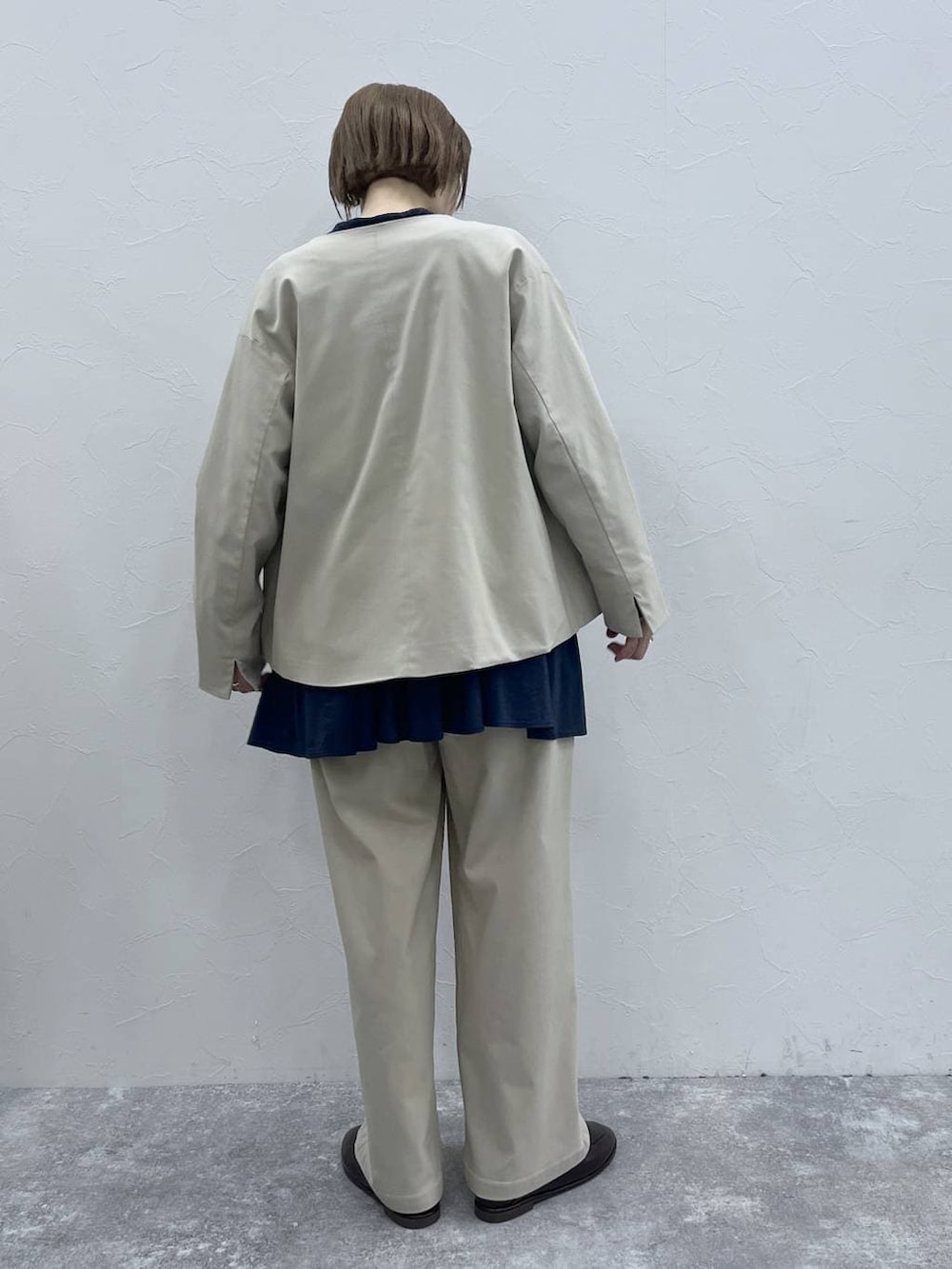 ベージュ系のスラックス、ベージュ系のノーカラージャケット、ブラウン系のローファーを着用したレディースの冬コーディネートの3枚目の写真