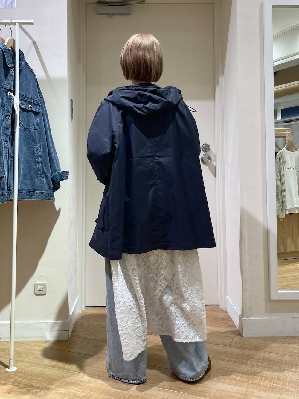 ブルー系のデニムパンツ、ブルー系のブルゾン、ホワイト系のベストを着用したレディースの春コーディネートの3枚目の写真