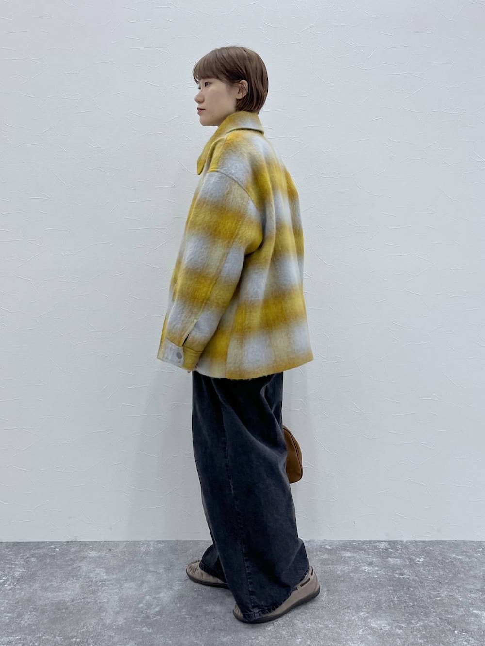 ブラック系のデニムパンツ、イエロー系のその他アウター、グレー系のモカシン/デッキシューズを着用したレディースの秋コーディネートの2枚目の写真