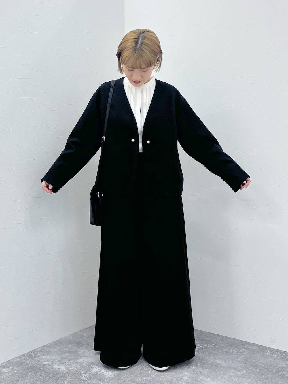 ブラック系のスーツセット、ホワイト系のシャツ/ブラウスを着用したレディースの秋コーディネートの2枚目の写真