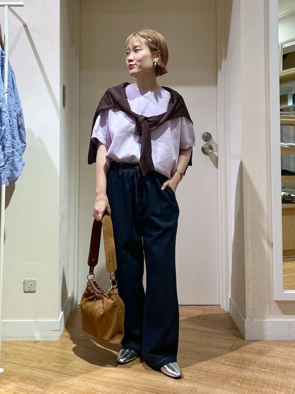 ブルー系のデニムパンツ、パープル系のスウェット、ブラウン系のショルダーバッグを着用したレディースの秋コーディネートの4枚目の写真