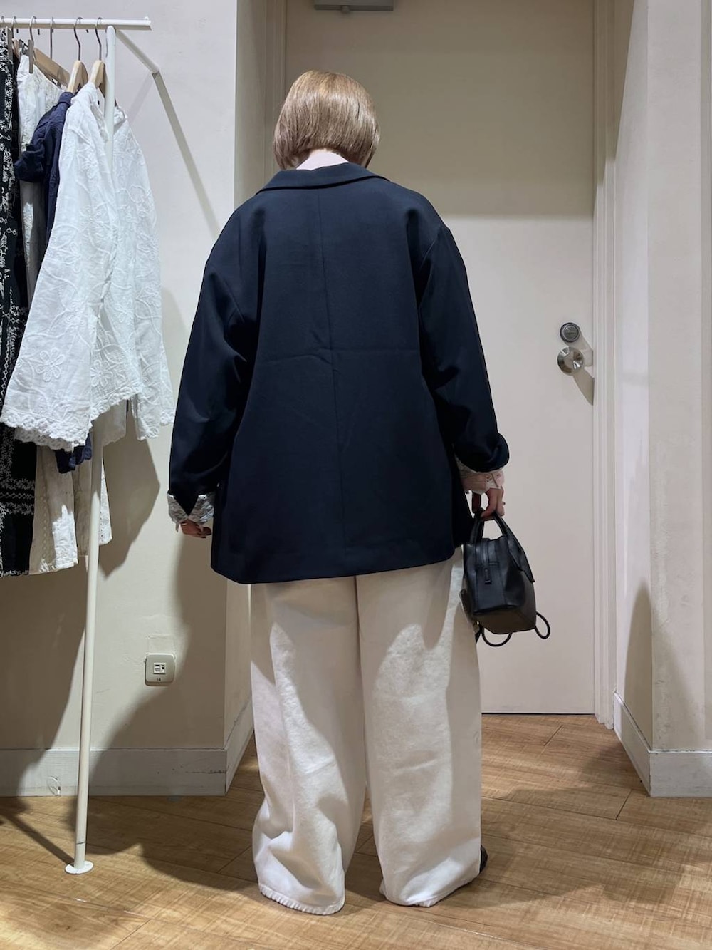 ホワイト系のデニムパンツ、ブルー系のテーラードジャケット、ブラック系のトートバッグを着用したレディースの冬コーディネートの3枚目の写真