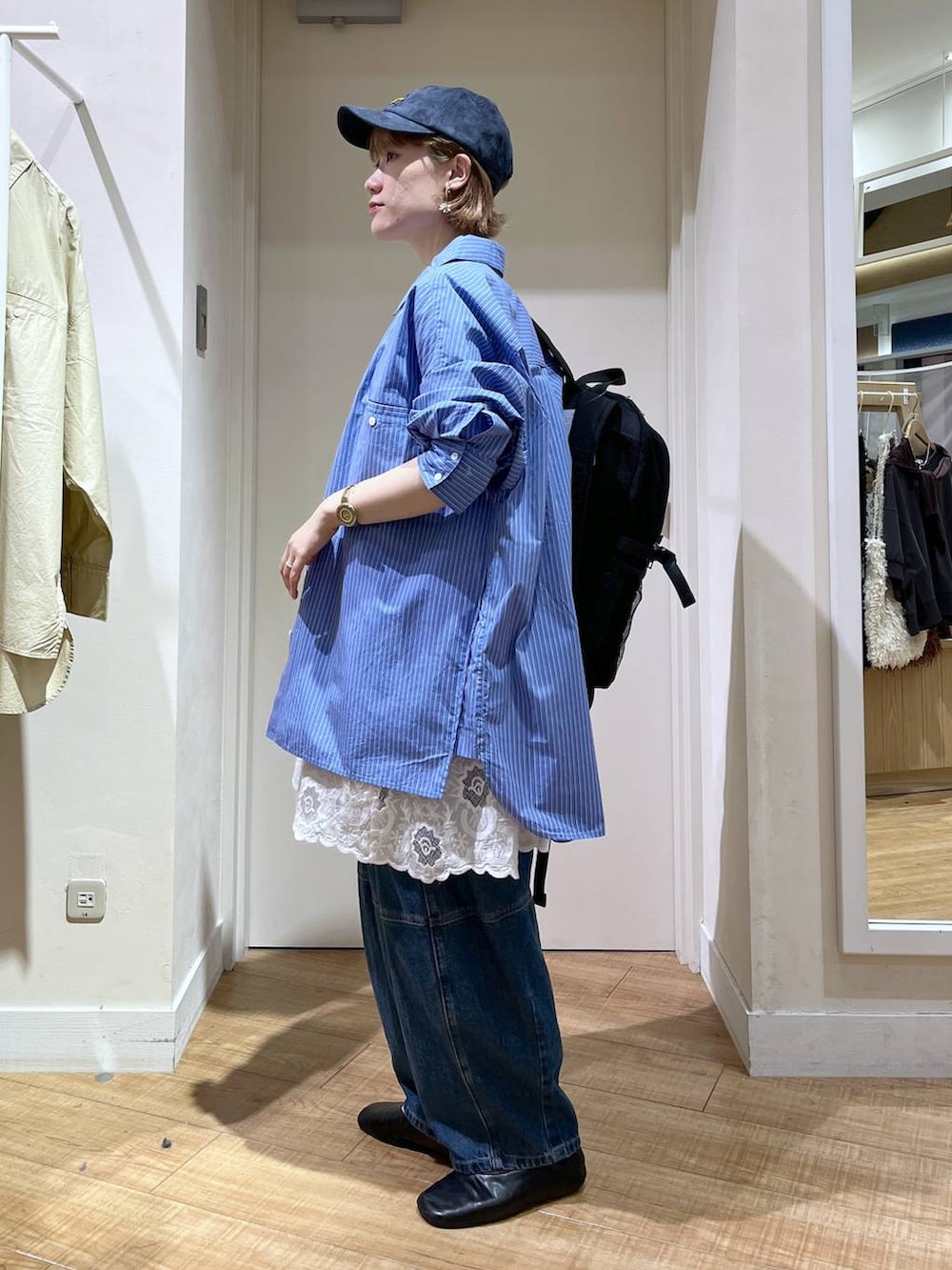 ブルー系のデニムパンツ、ホワイト系のチュニック、ブラック系のバックパック/リュックを着用したレディースの秋コーディネートの3枚目の写真