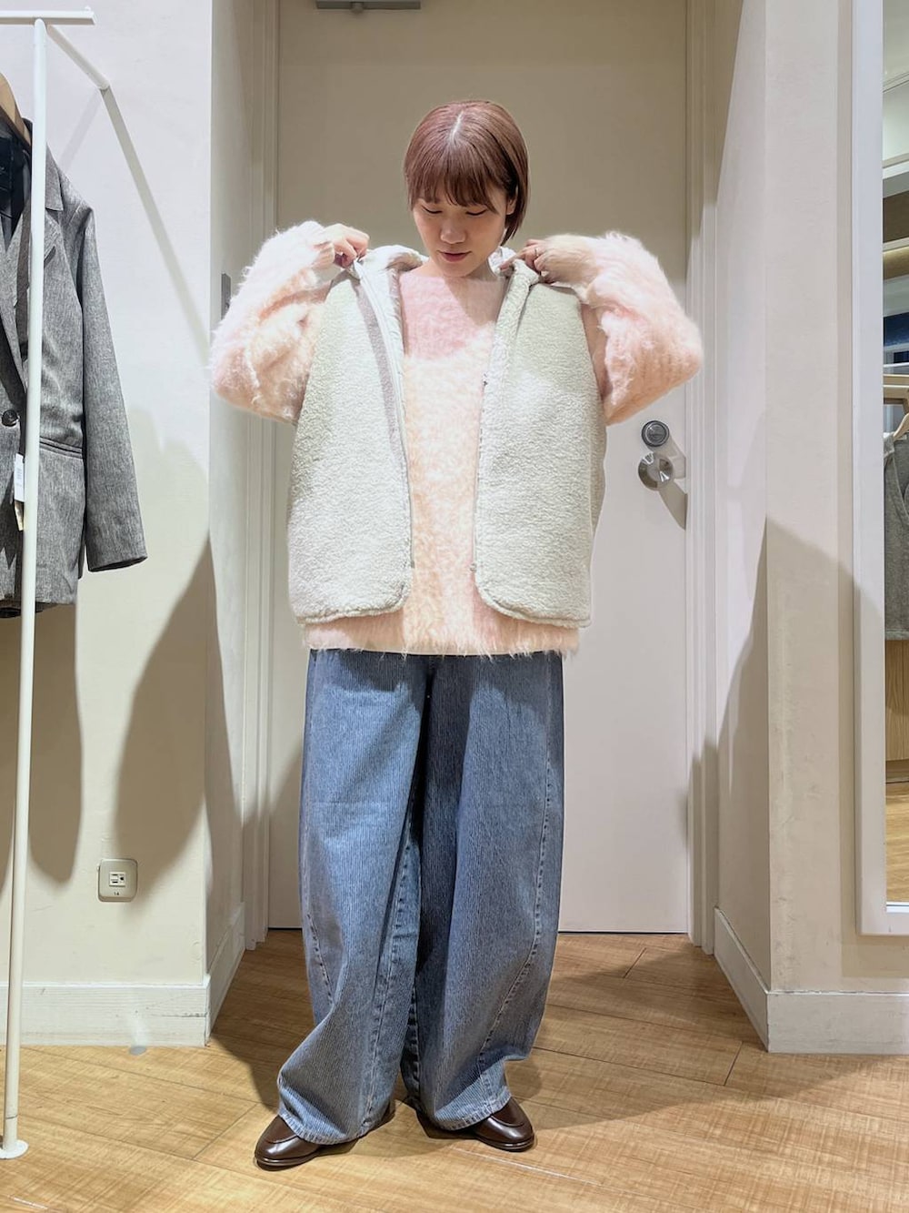 ブラウン系のベスト、ピンク系のニット/セーター、ブルー系のデニムパンツを着用したレディースの冬コーディネートの2枚目の写真