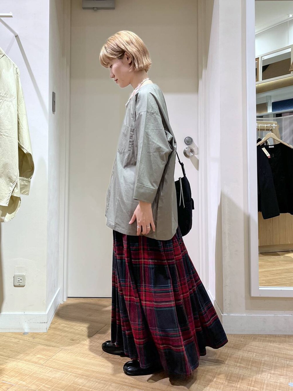 グリーン系のブルゾン、ブラック系のトートバッグ、レッド系のスカートを着用したレディースの秋コーディネートの2枚目の写真