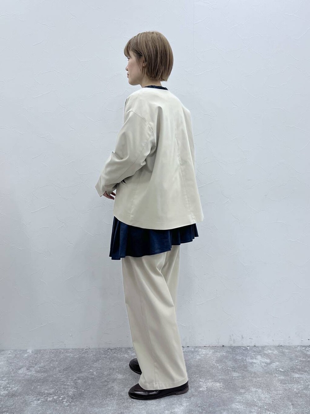 ベージュ系のスラックス、ベージュ系のノーカラージャケット、ブラウン系のローファーを着用したレディースの冬コーディネートの2枚目の写真