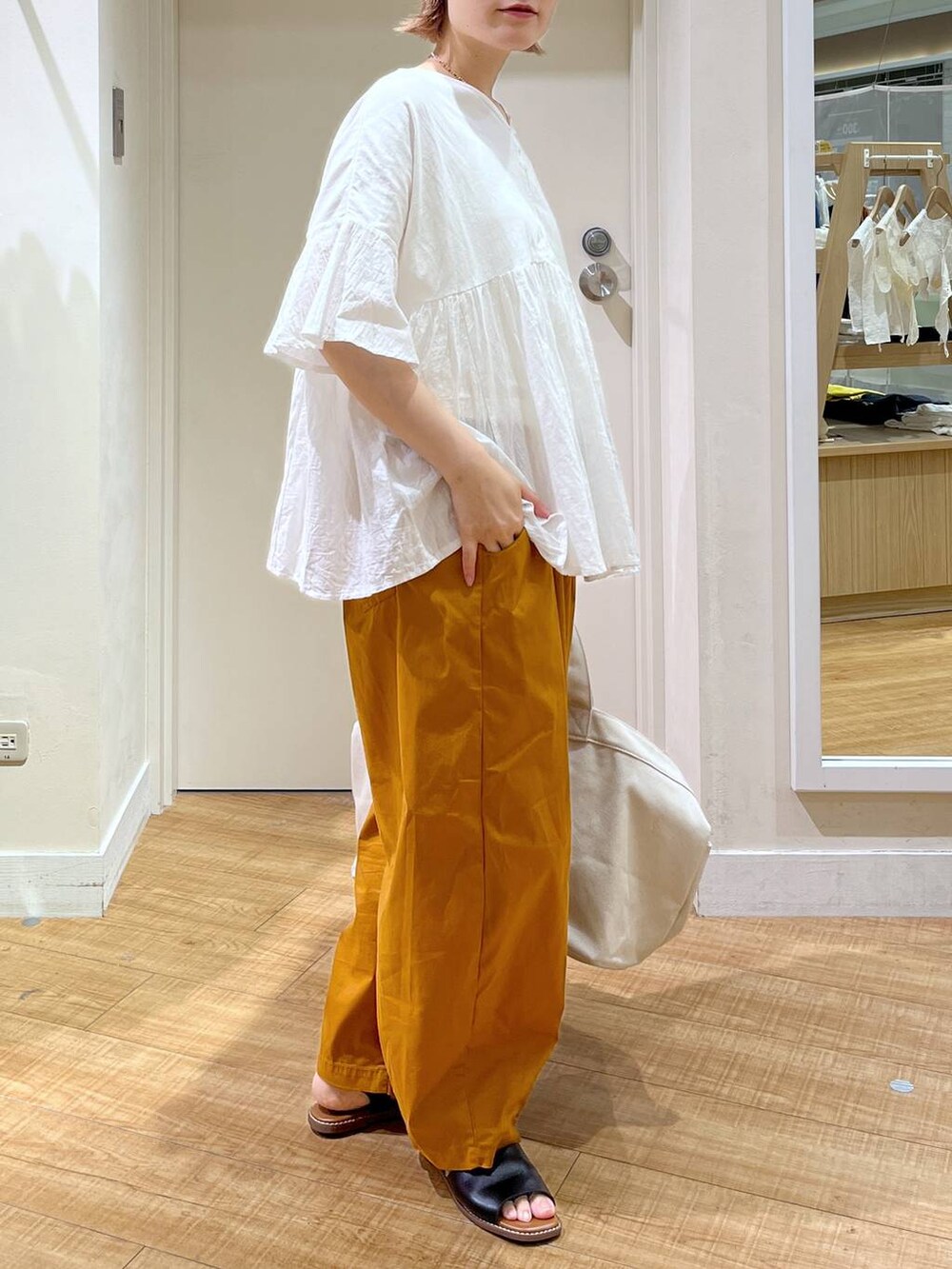 ブラック系のサンダル、イエロー系のその他パンツ、ホワイト系のTシャツ/カットソーを着用したレディースの夏コーディネートの3枚目の写真
