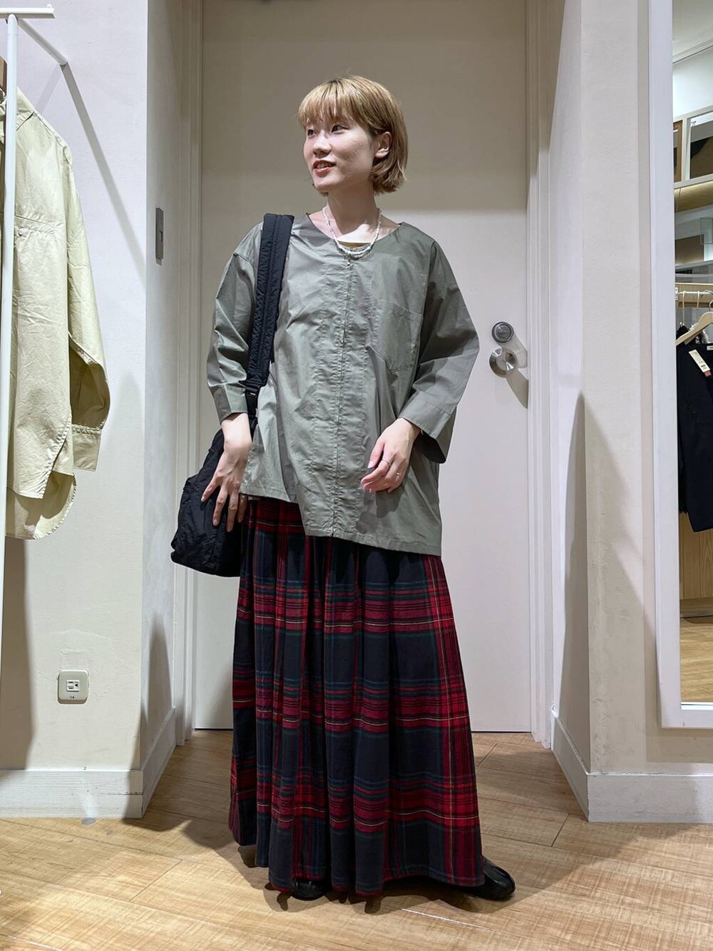 グリーン系のブルゾン、ブラック系のトートバッグ、レッド系のスカートを着用したレディースの秋コーディネートの4枚目の写真