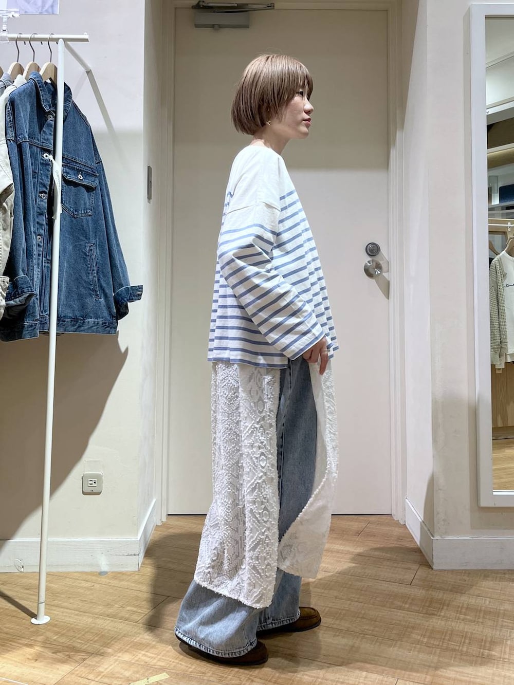 ブルー系のデニムパンツ、ブルー系のブルゾン、ホワイト系のベストを着用したレディースの春コーディネートの5枚目の写真