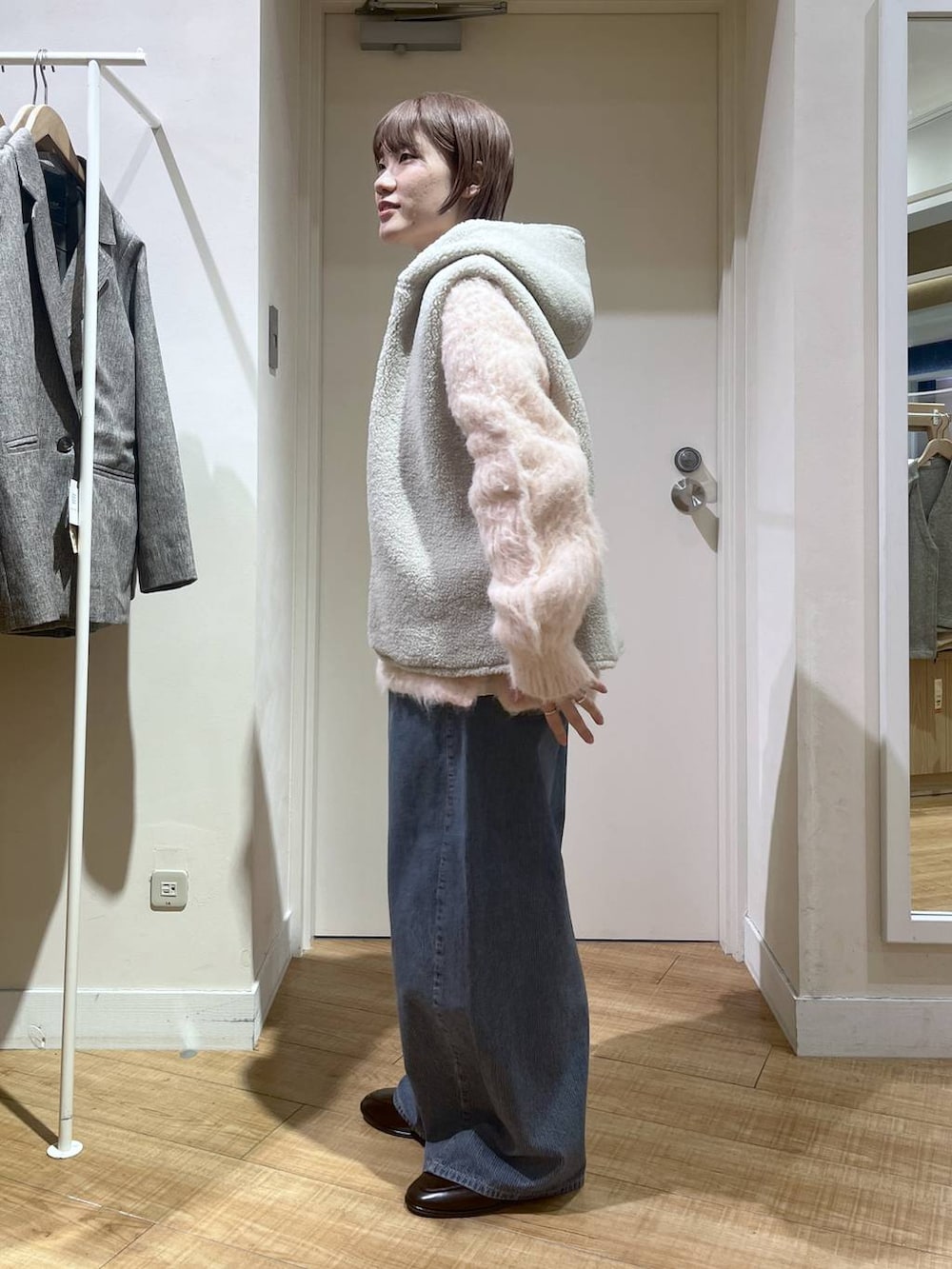 ブラウン系のベスト、ピンク系のニット/セーター、ブルー系のデニムパンツを着用したレディースの冬コーディネートの3枚目の写真