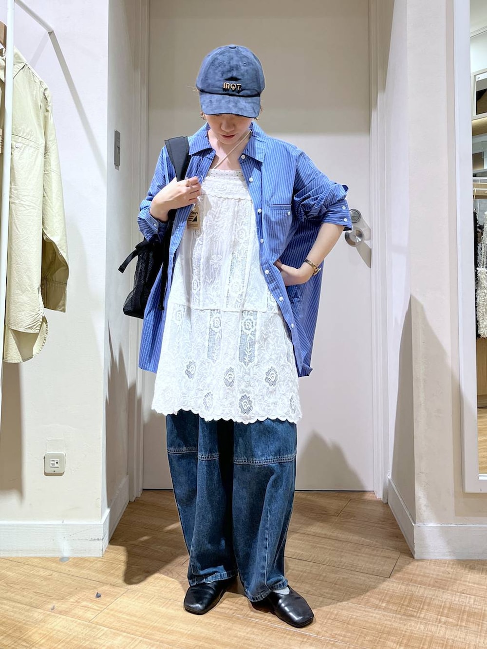 ブルー系のデニムパンツ、ホワイト系のチュニック、ブラック系のバックパック/リュックを着用したレディースの秋コーディネートの2枚目の写真