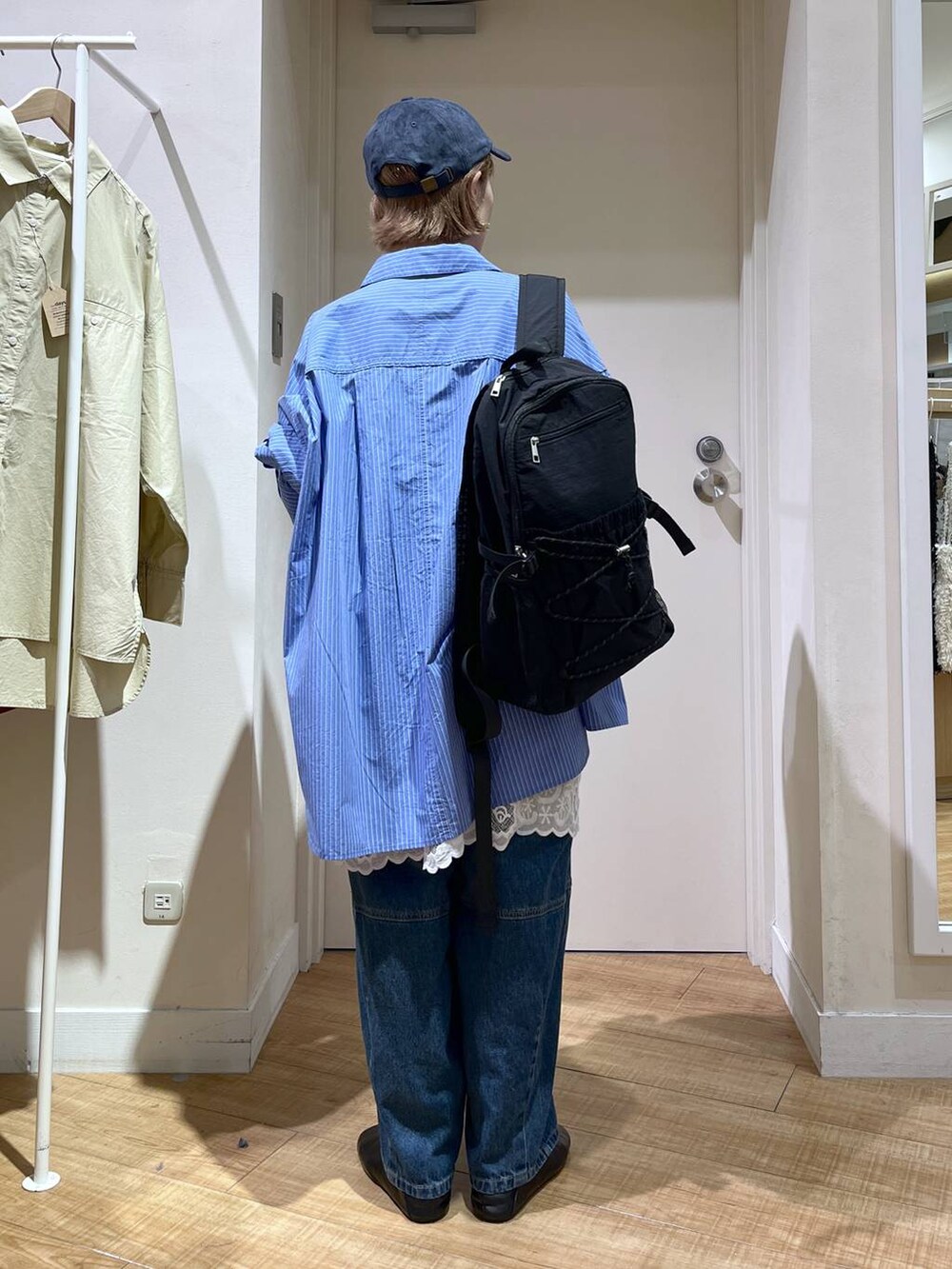 ブルー系のデニムパンツ、ホワイト系のチュニック、ブラック系のバックパック/リュックを着用したレディースの秋コーディネートの4枚目の写真