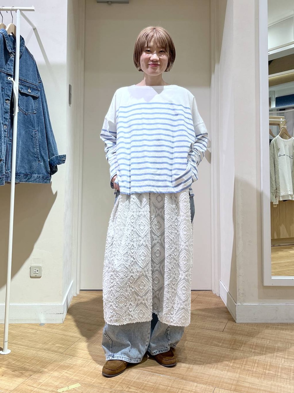 ブルー系のデニムパンツ、ブルー系のブルゾン、ホワイト系のベストを着用したレディースの春コーディネートの4枚目の写真