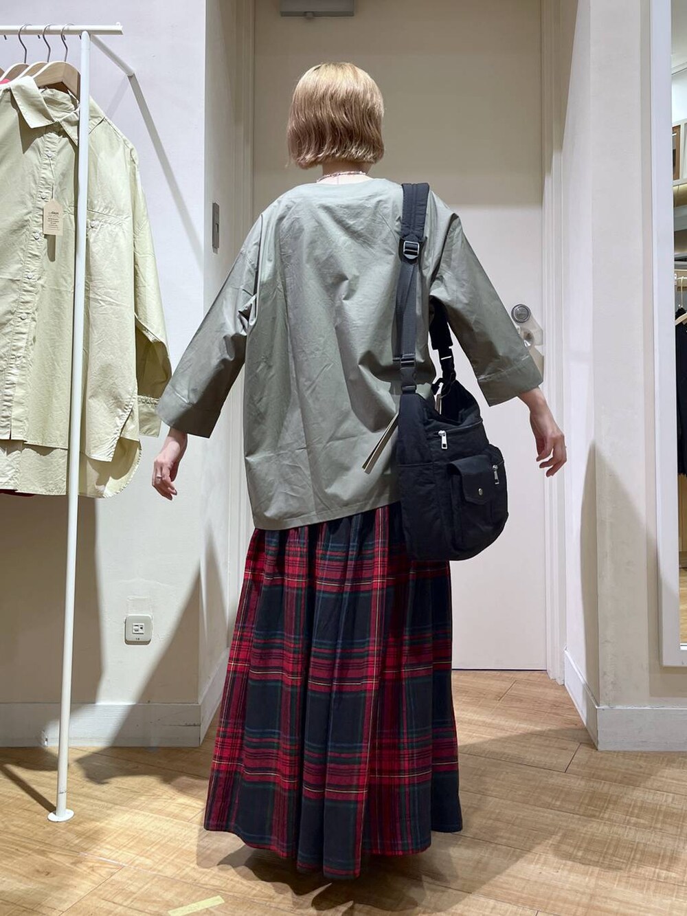 グリーン系のブルゾン、ブラック系のトートバッグ、レッド系のスカートを着用したレディースの秋コーディネートの3枚目の写真