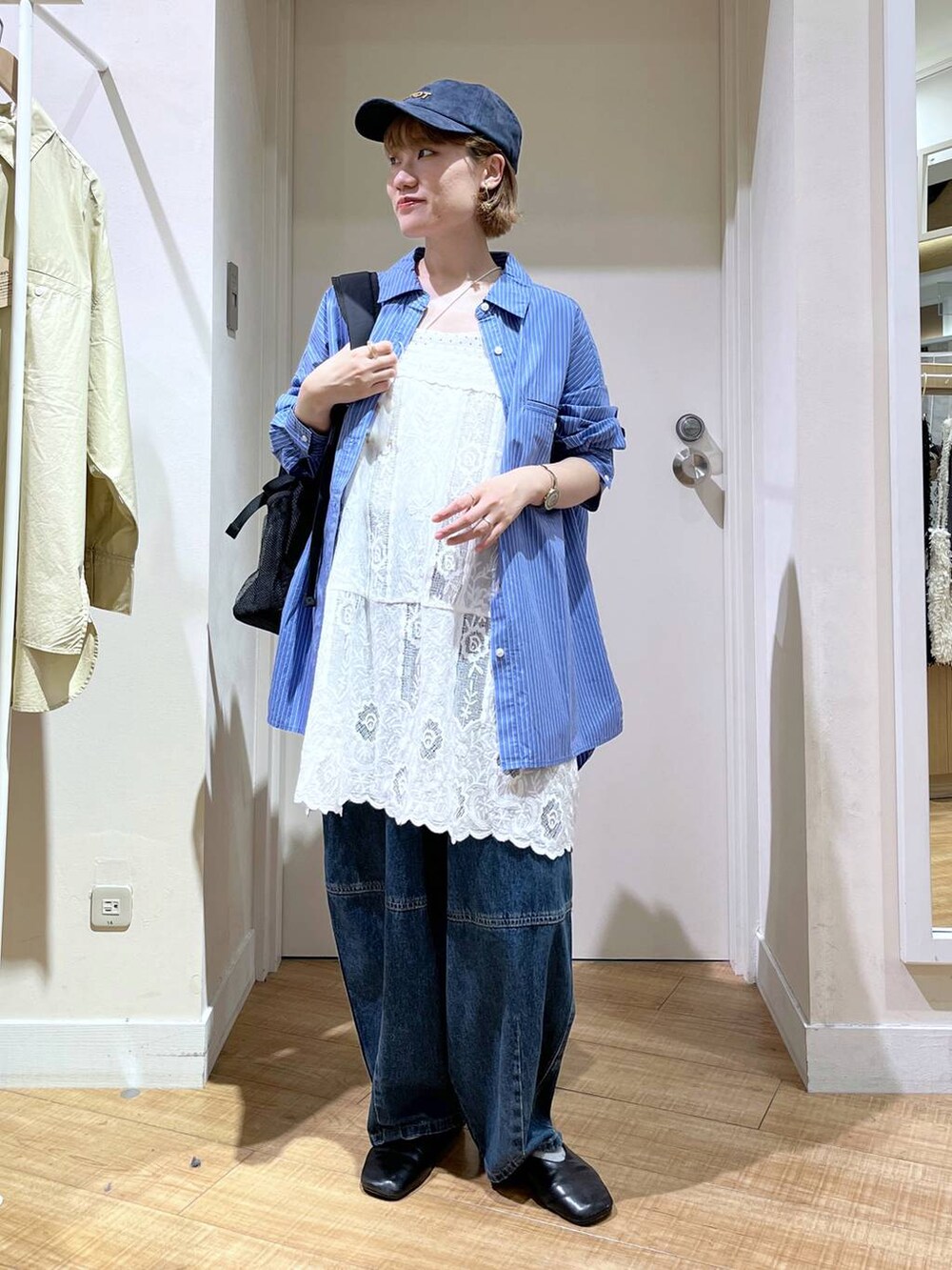 ブルー系のデニムパンツ、ホワイト系のチュニック、ブラック系のバックパック/リュックを着用したレディースの秋コーディネートの5枚目の写真