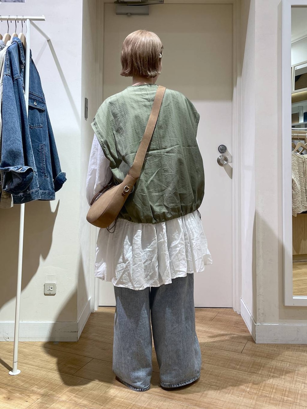 ブルー系のデニムパンツ、ブラウン系のトートバッグ、ホワイト系のシャツ/ブラウスを着用したレディースの春コーディネートの3枚目の写真