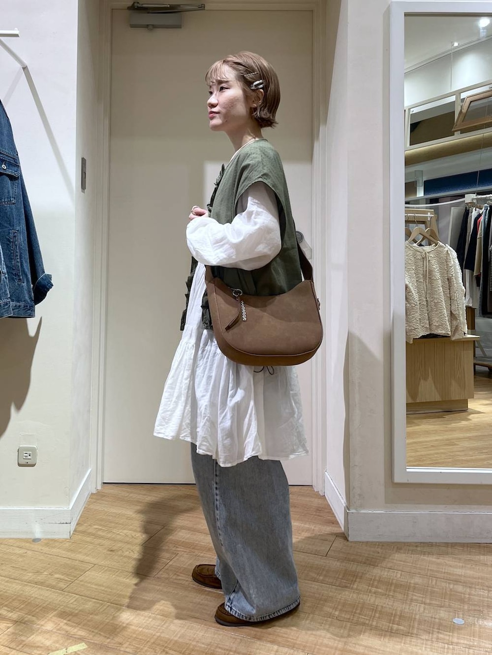 ブルー系のデニムパンツ、ブラウン系のトートバッグ、ホワイト系のシャツ/ブラウスを着用したレディースの春コーディネートの2枚目の写真