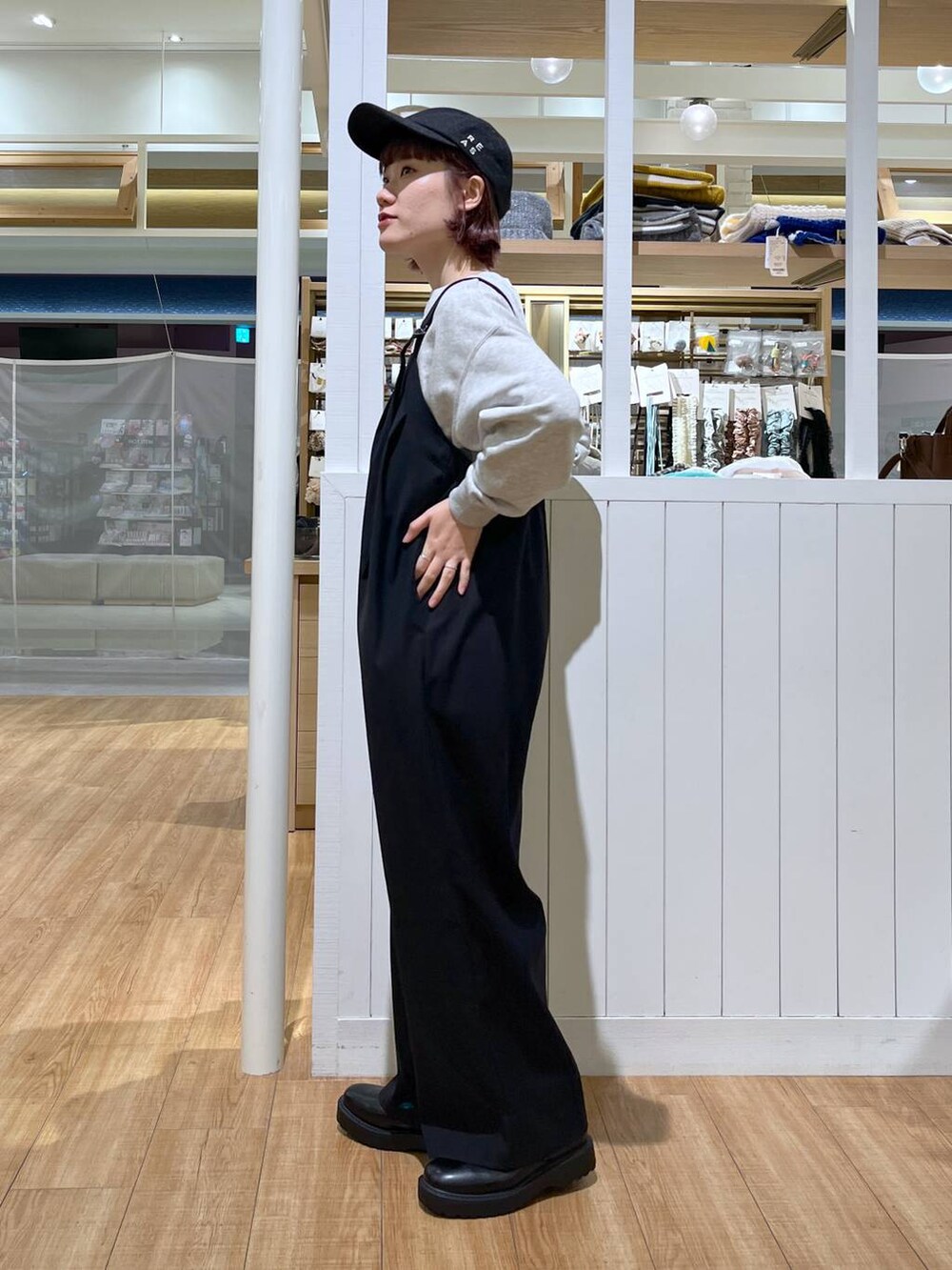 グレー系のスウェット、ブラック系のサロペット/オーバーオール、ブラック系のブーツを着用したレディースの秋コーディネートの5枚目の写真