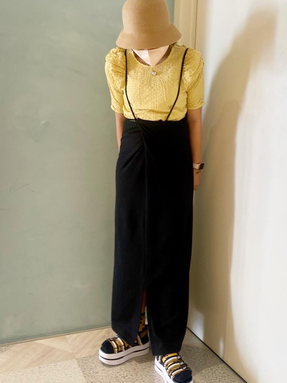 イエロー系のシャツ/ブラウス、ブラック系のワンピース、ベージュ系のハットを着用したレディースの夏コーディネートの2枚目の写真