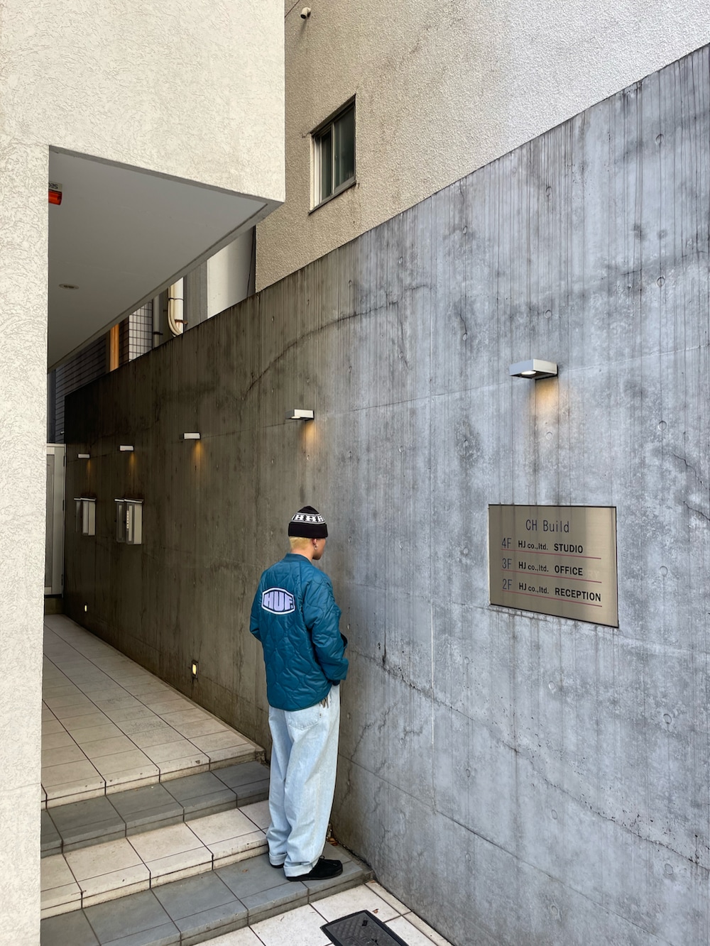 ブルー系のデニムパンツ、ブラック系のモカシン/デッキシューズ、グリーン系のブルゾンを着用したメンズの秋コーディネートの2枚目の写真