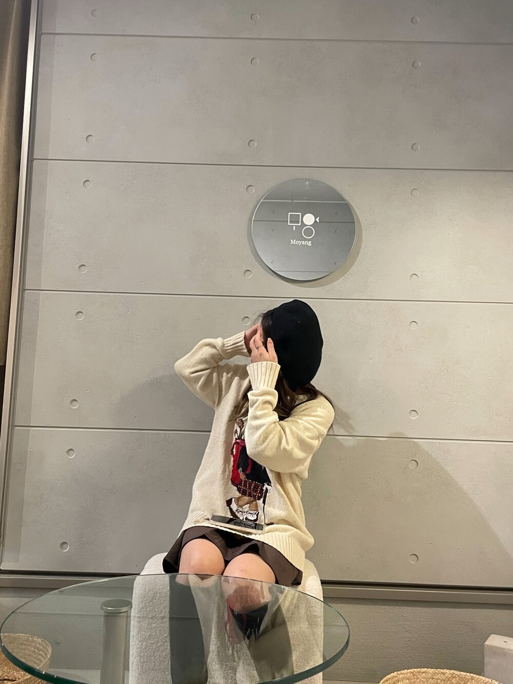 ブラック系のブーツ、ブラウン系のスカート、ベージュ系のニット/セーターを着用したレディースの秋コーディネートの2枚目の写真