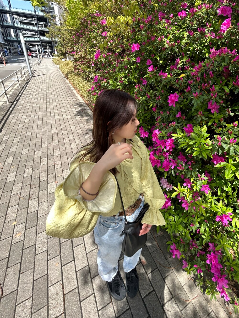 イエロー系のトップス、ブラック系のスニーカーを着用したレディースの春コーディネートの2枚目の写真