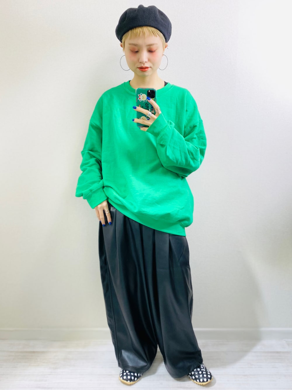 グリーン系のスウェット、ブラック系のブルゾン、ブラック系のスニーカーを着用したレディースの秋コーディネートの2枚目の写真