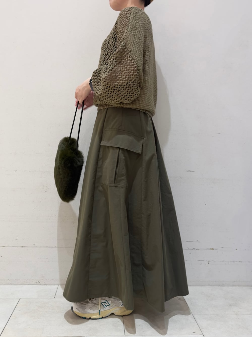 グリーン系のニット/セーター、グリーン系のハンドバッグ、グリーン系のスカートを着用したレディースの秋コーディネートの2枚目の写真