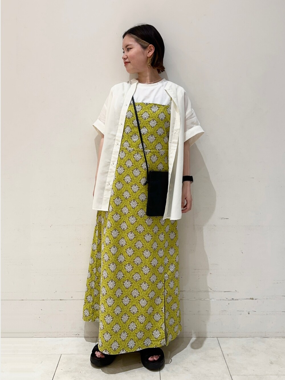 ホワイト系のTシャツ/カットソー、イエロー系のワンピース、ブラック系のハンドバッグを着用したレディースの春コーディネートの2枚目の写真