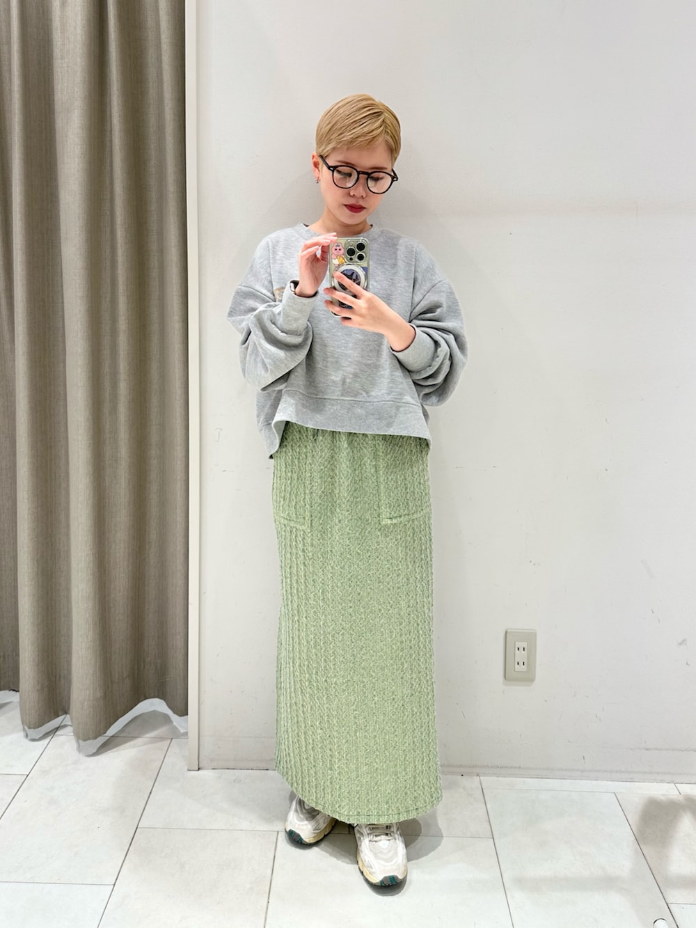 グリーン系のスカート、グレー系のTシャツ/カットソー、ブラック系のハンドバッグを着用したレディースの冬コーディネートの3枚目の写真