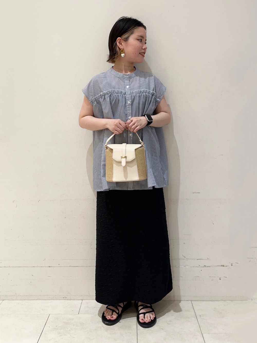 ブルー系のシャツ/ブラウス、ブラック系のスカート、ホワイト系のハンドバッグを着用したレディースの春コーディネートの2枚目の写真